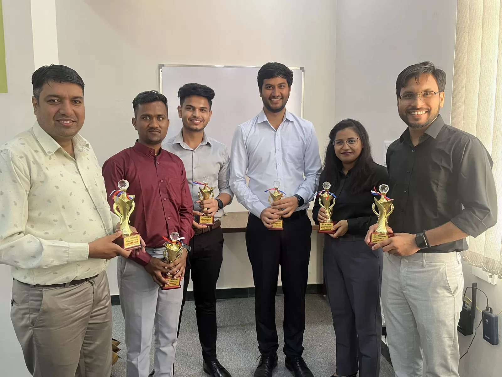 Techshlok team members holding annual award trophies