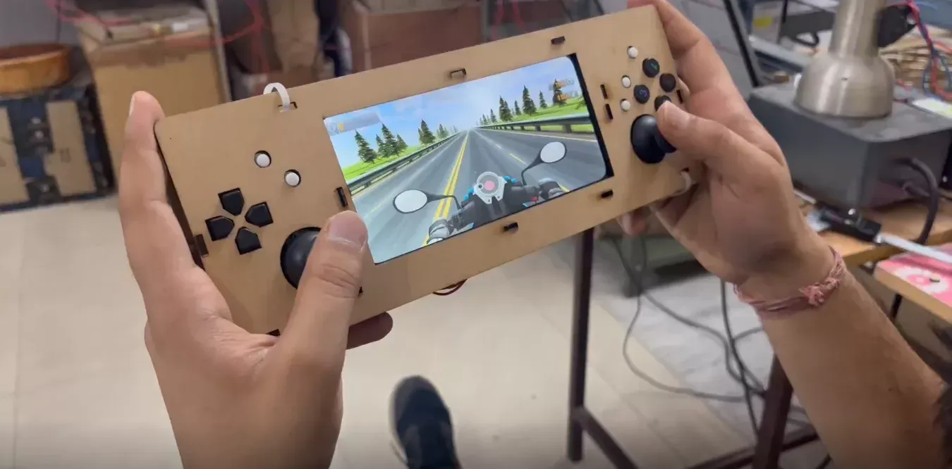 Early handheld console prototype built from laser-cut MDF, with a phone screen standing in for the display