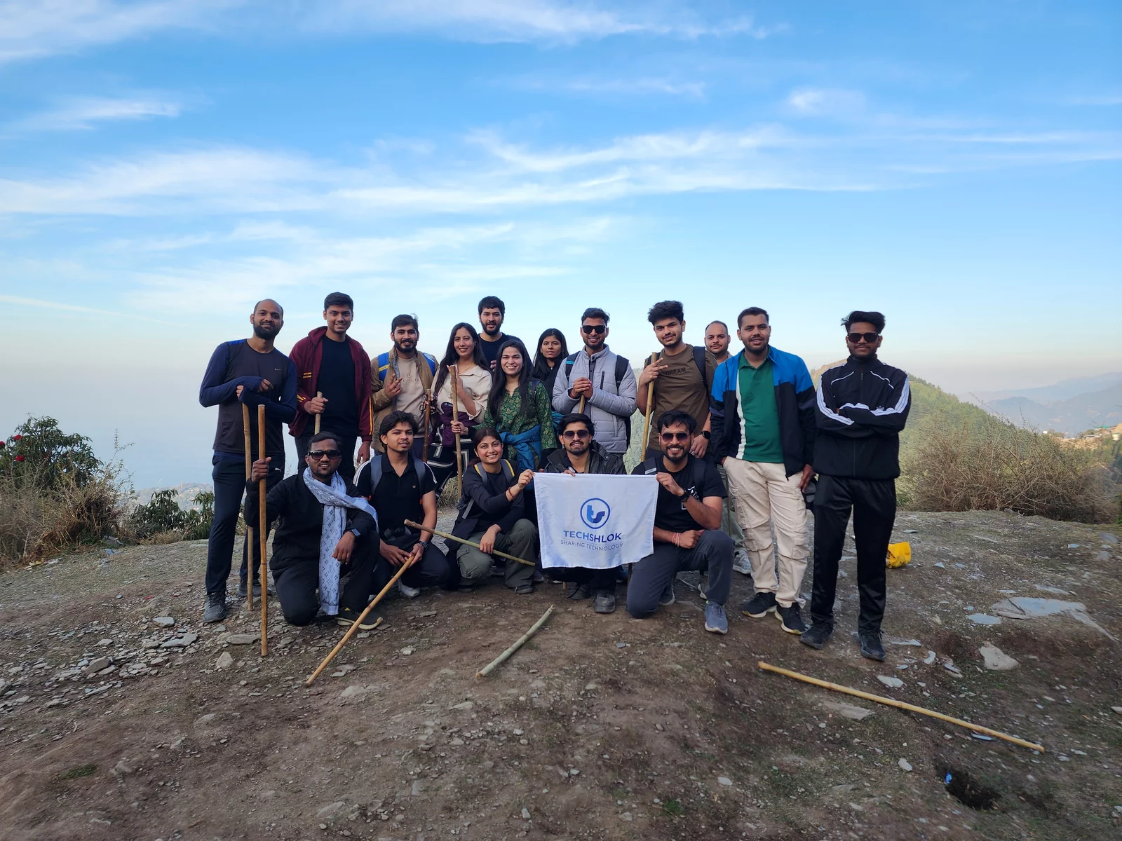 The team on a mountain trek, holding the Techshlok flag at the summit
