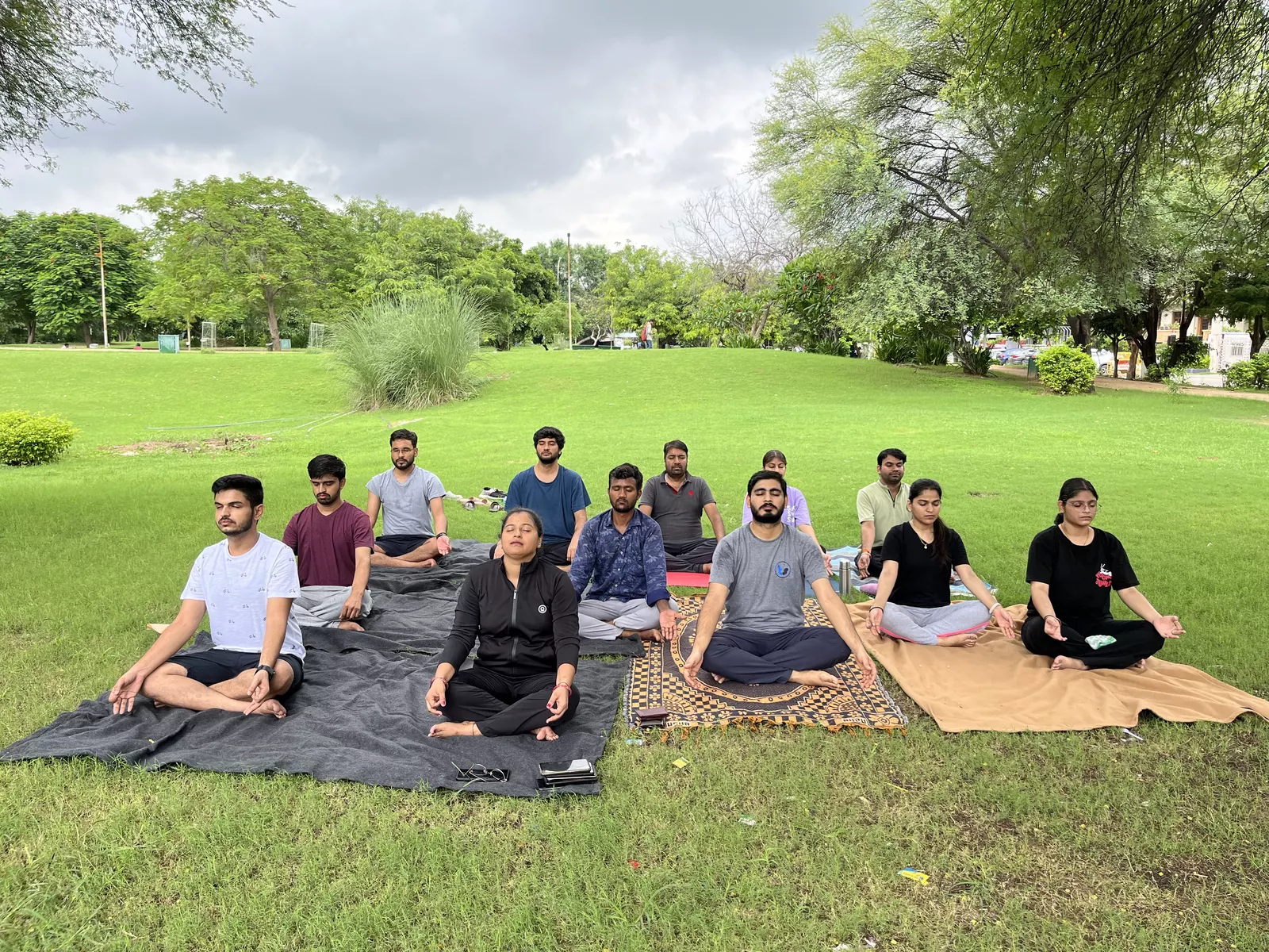 The team in a group meditation session on the grass in a park